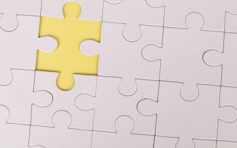 All-white jigsaw puzzle with one piece highlighted yellow.